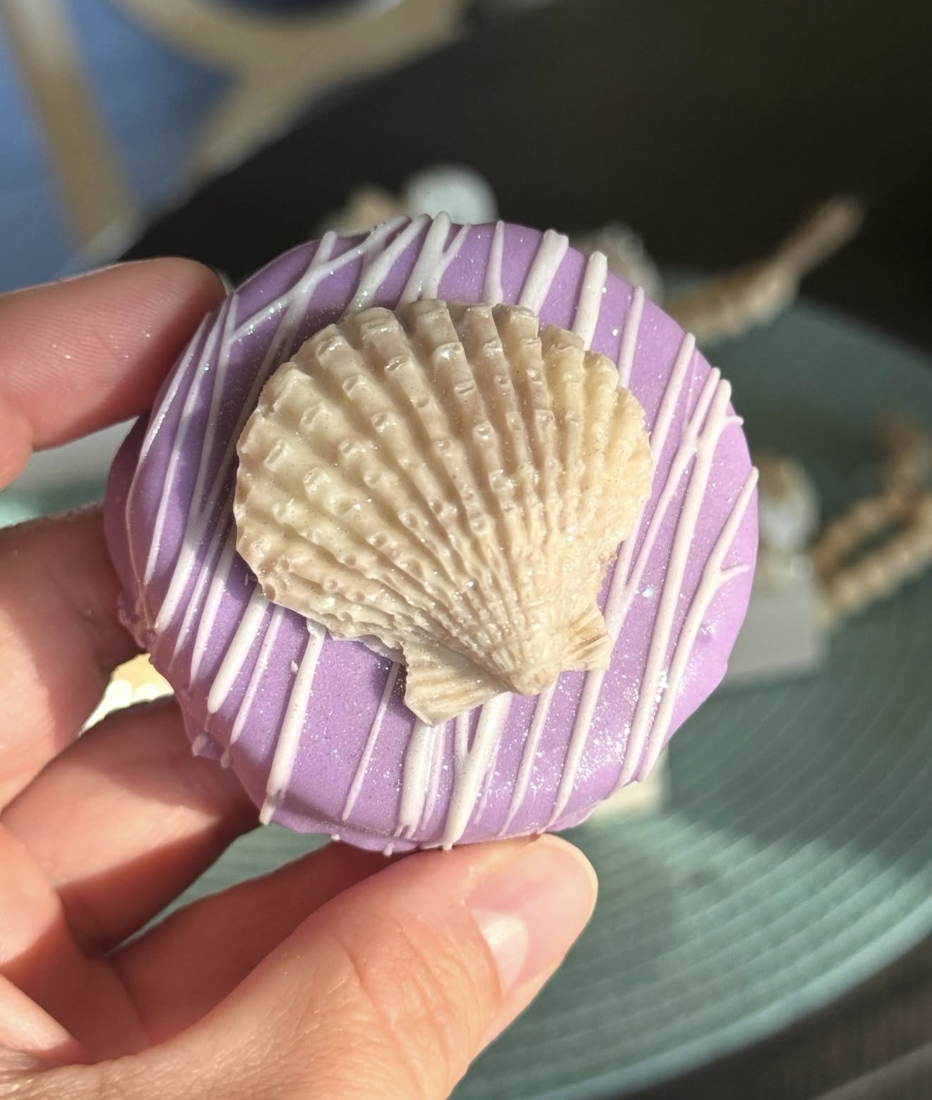 Purple dipped Oreo with large scallop shell topper held in hand