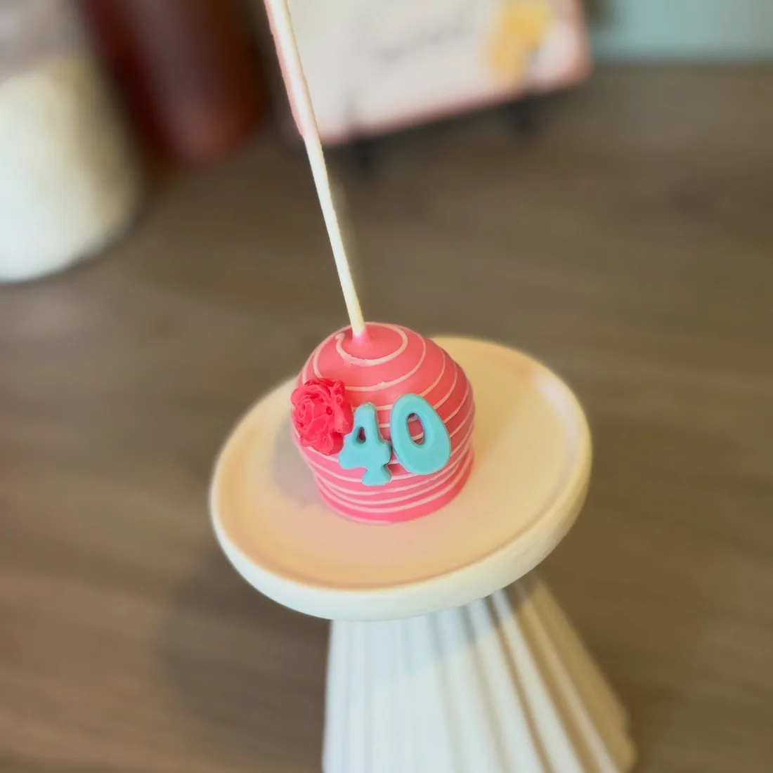 Pink striped cake pop with a teal 40 and a red piped rose