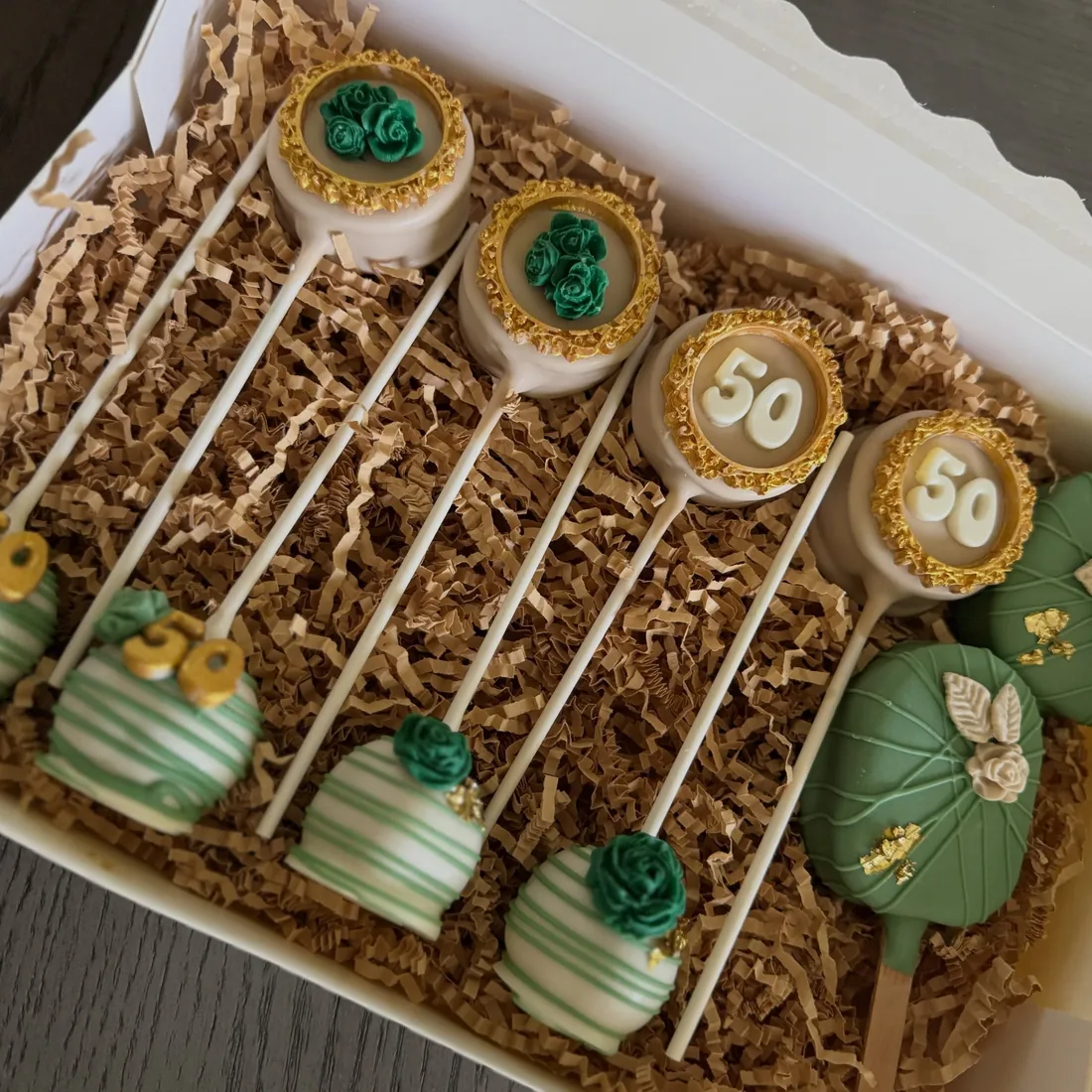 Gift box of 50th birthday cake pops in emerald green and gold