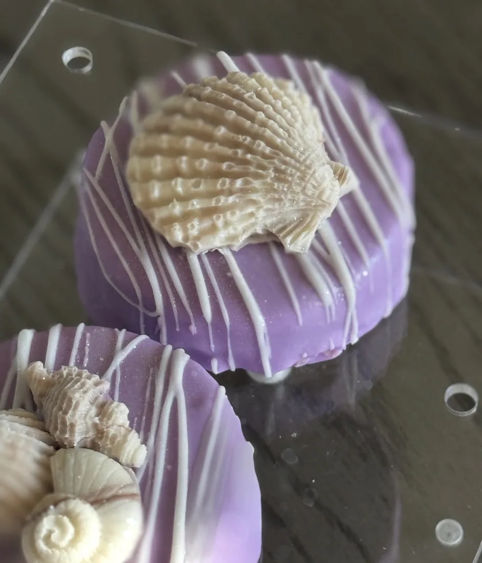 Purple dipped cake pucks topped with white chocolate scallop and snail shells