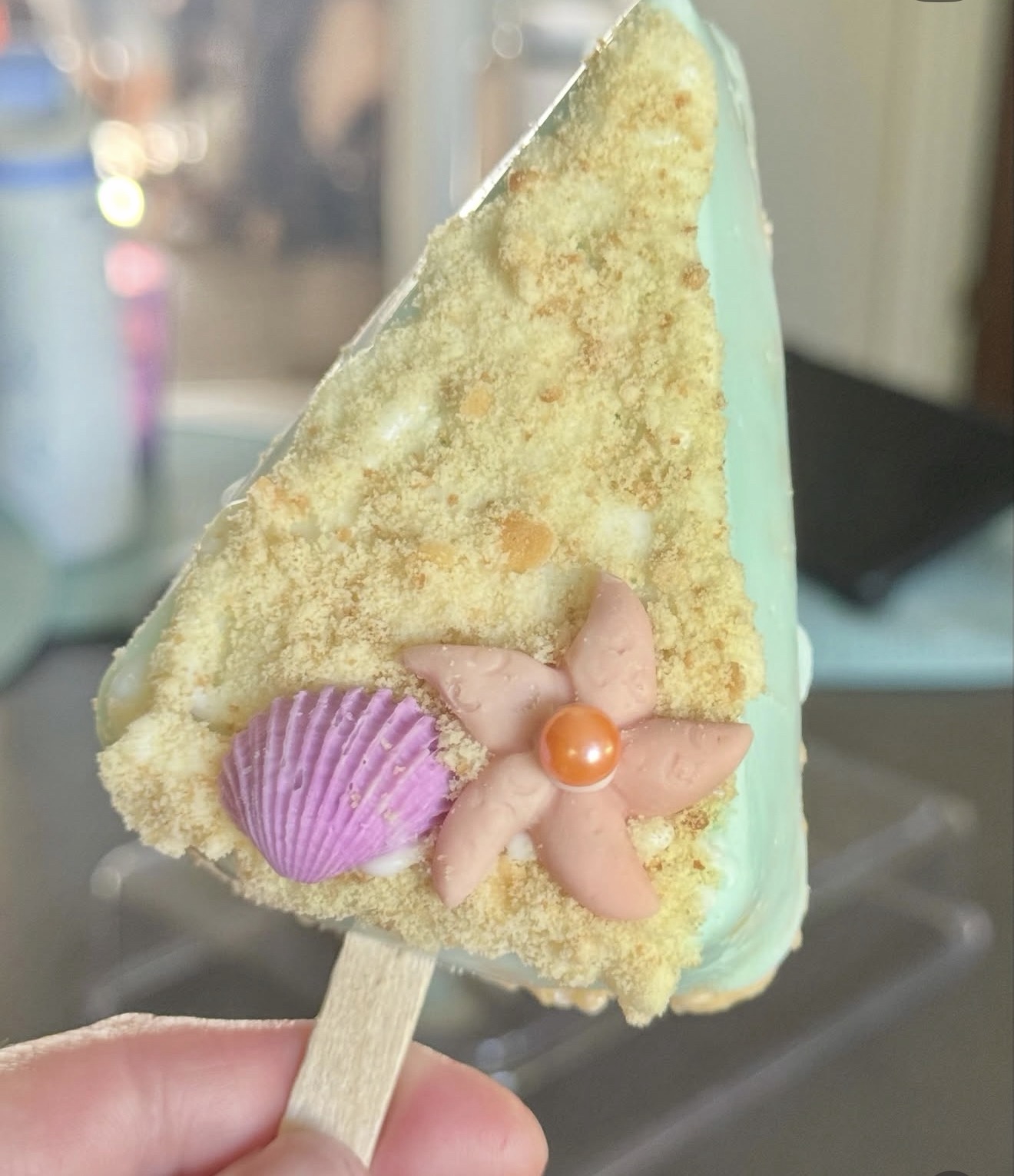 Mint rice crispy treat dipped in white chocolate with starfish and purple scallop shell on sandy base