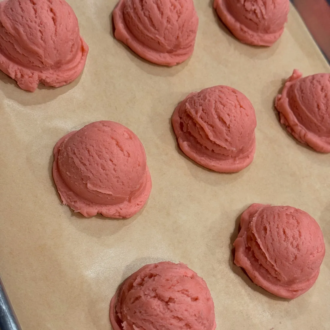 Tray of freshly scooped pink cookie dough ready for the oven