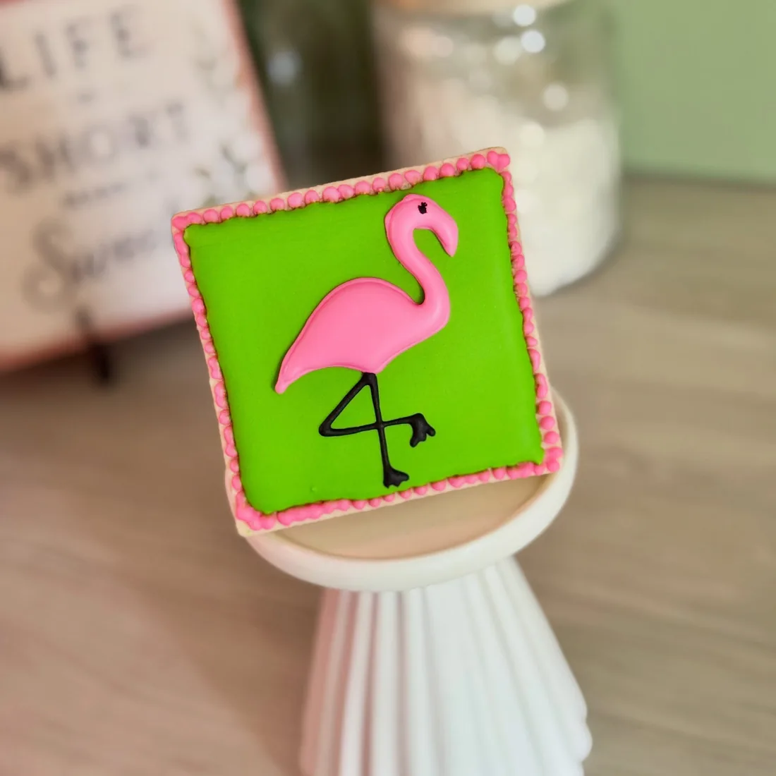 Lime green square cookie with a hand-piped pink flamingo and a pink border