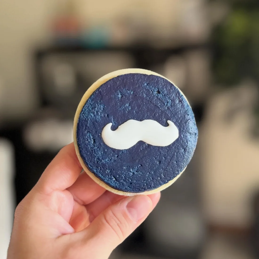Navy textured round cookie with a white fondant mustache
