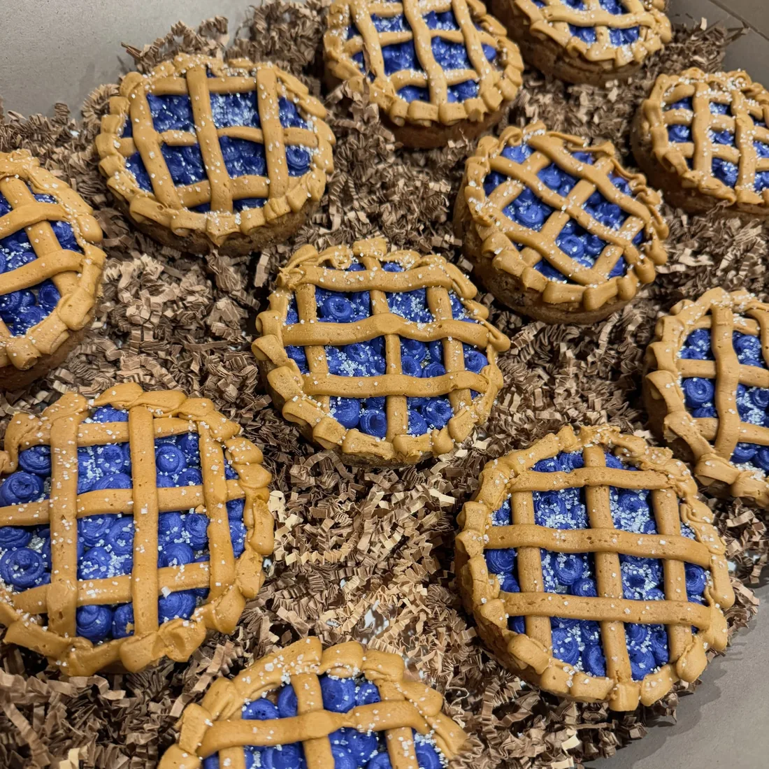 Tray of mini blueberry cookie pies with piped buttercream lattices