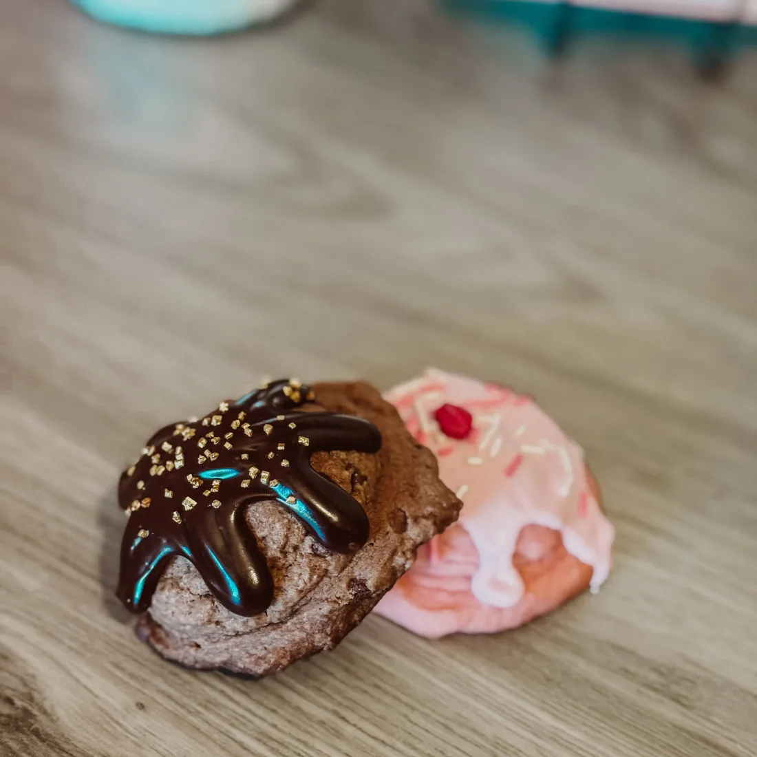 A chocolate ganache cookie beside a pink strawberry cookie with white drizzle