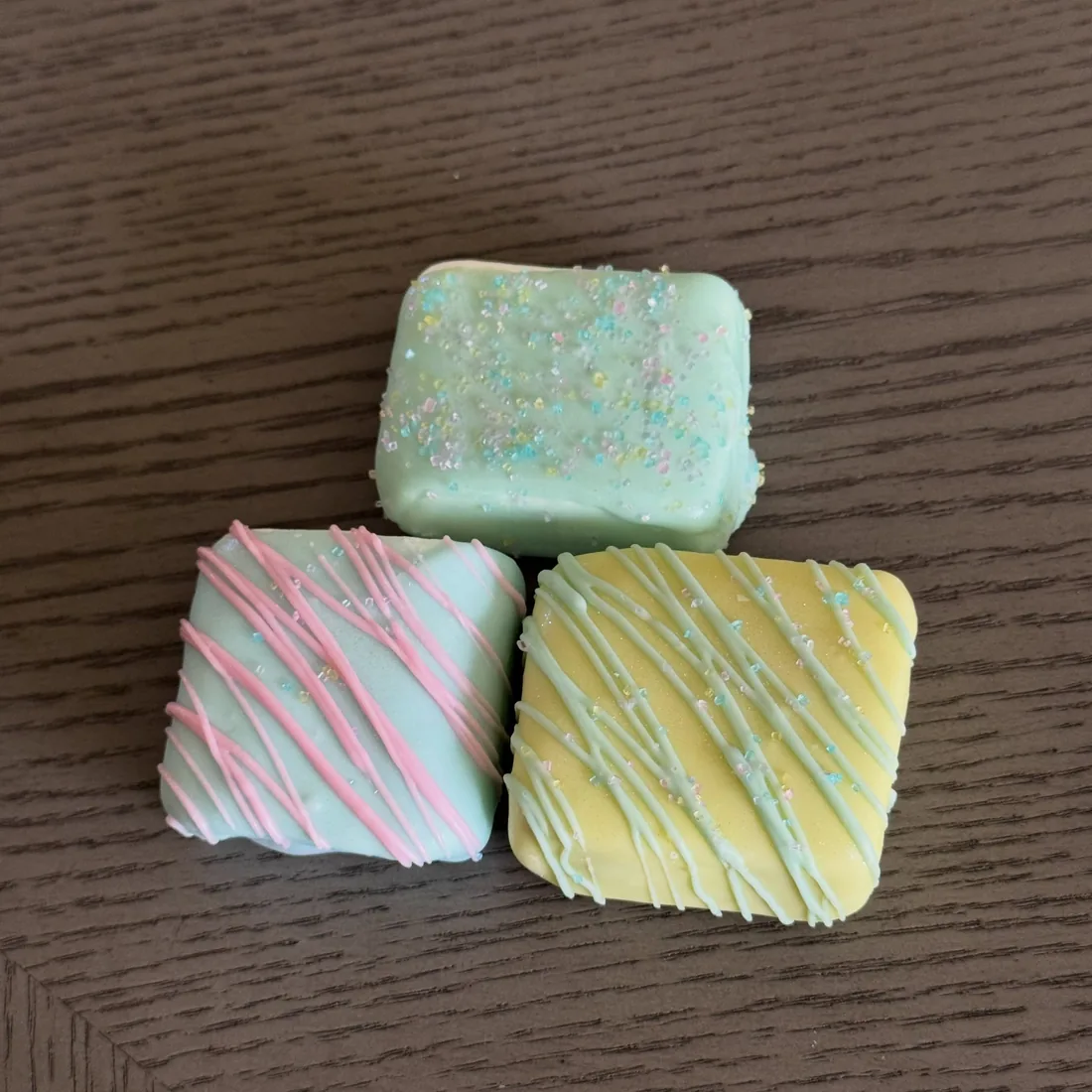 Three marshmallows dipped in mint, blue and lemon white chocolate with drizzle and pastel sprinkles
