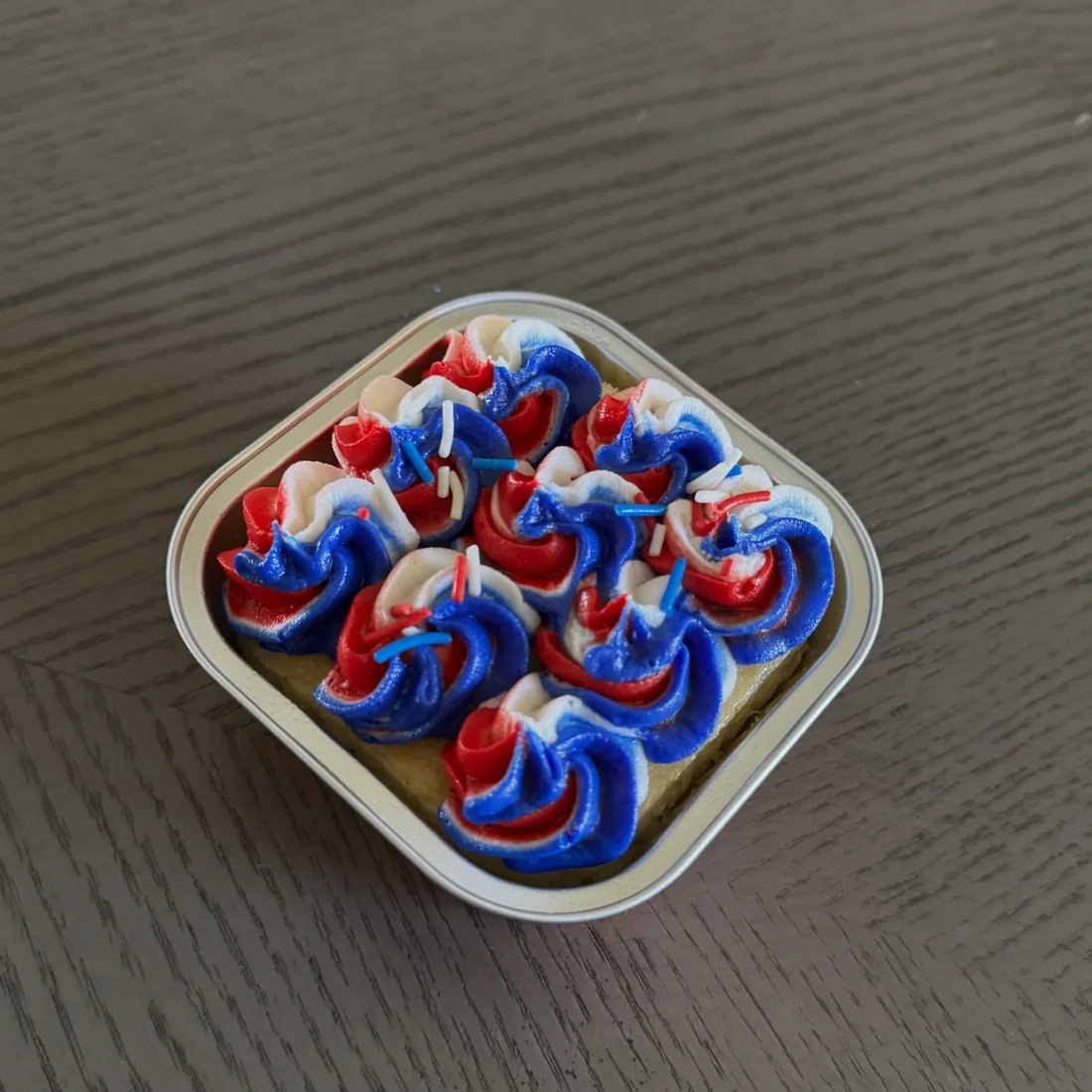 Mini cake covered in red, white and blue buttercream rosettes in a square container