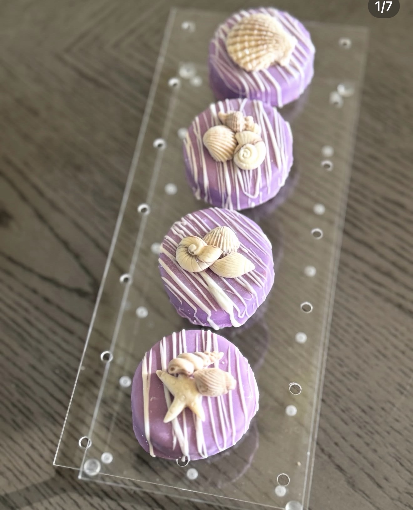 Four purple dipped Oreos with different shell and sea creature toppers arranged on acrylic tray