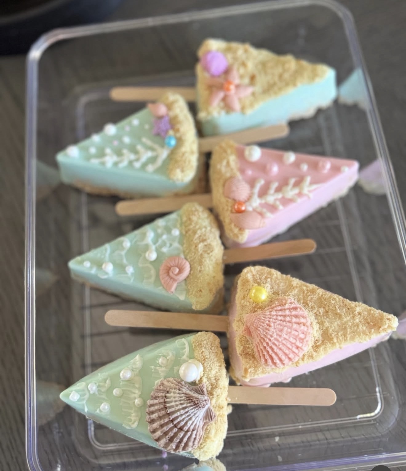 Full set of beach themed rice crispy treats dipped in white chocolate in mint and pink, with shells and sea life decorations