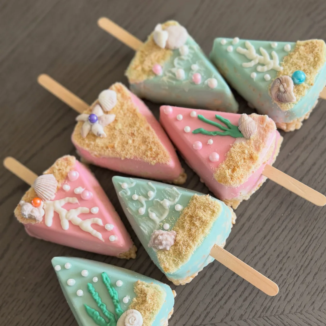 Six triangle beach Rice Krispie treats in mint and pink with shells, coral and sandy crumble